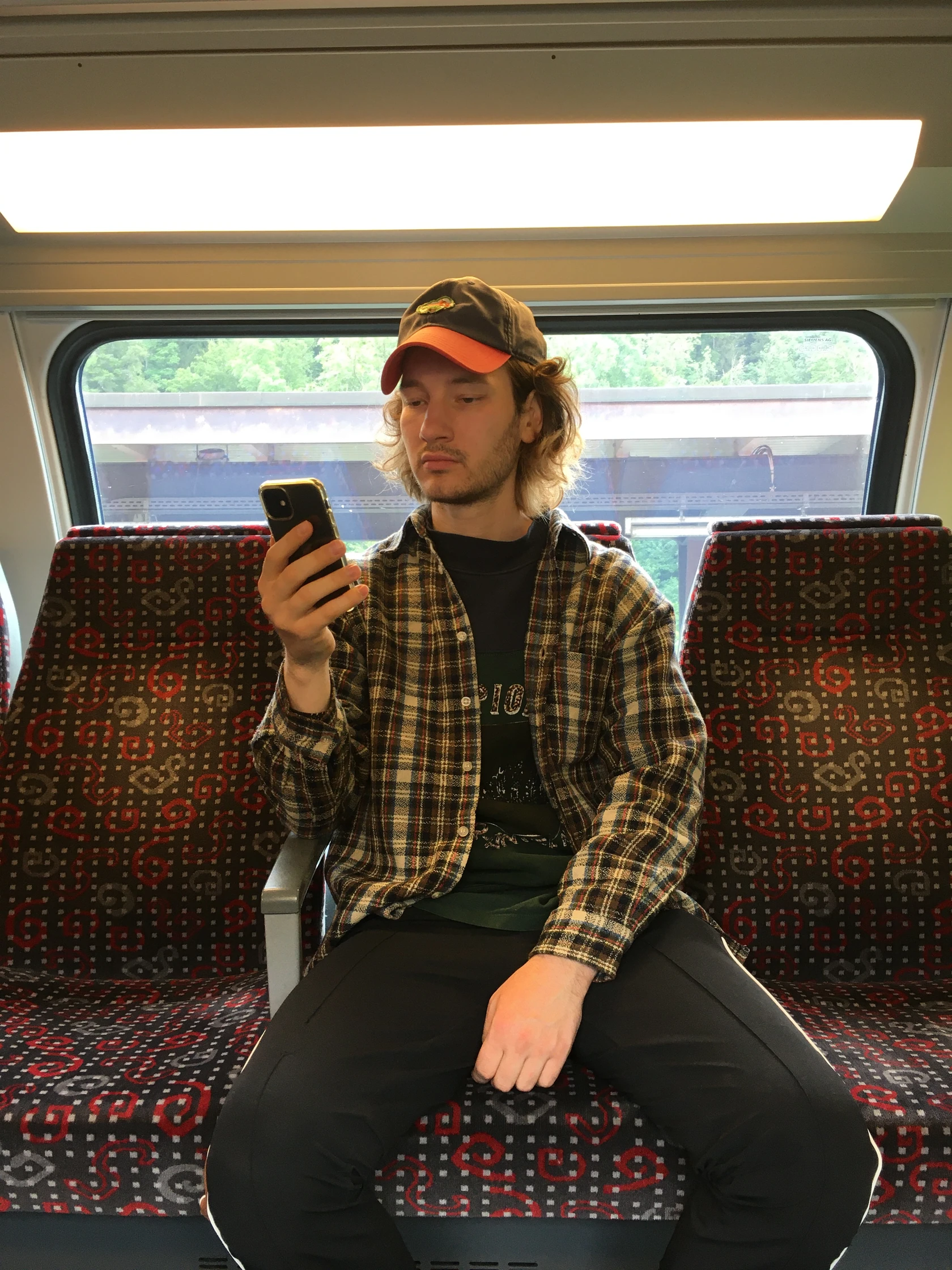 A person sitting on a train and looking at a phone.